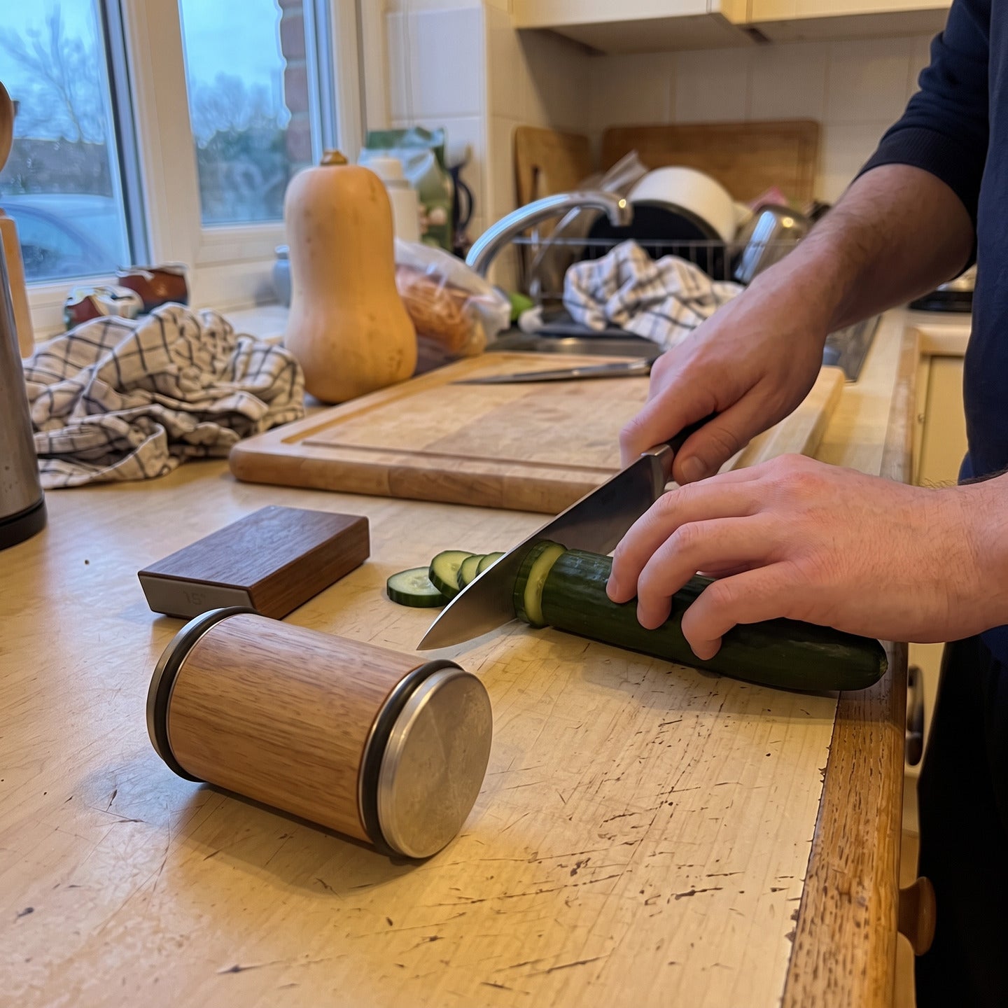 Owner slicing cucumber for dinner with the Cutwell roller and magnetic guide beside the board